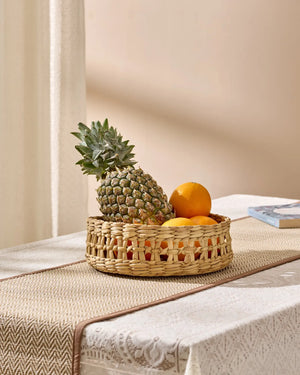 Woven wicker fruit basket with pineapple and oranges in natural tan hue