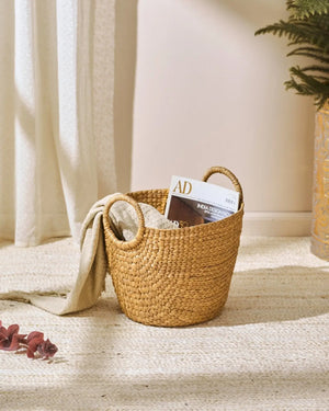 Golden-brown wicker basket with handles in water hyacinth decor