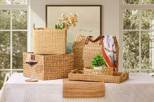 Wicker baskets and a glass of wine on a table with a window in the background