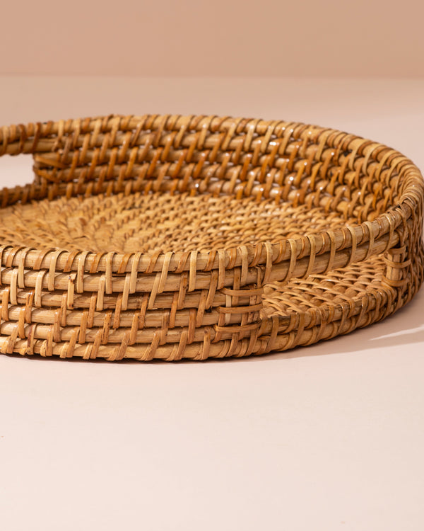 Round woven rattan tray in natural tan with intricate interlaced pattern