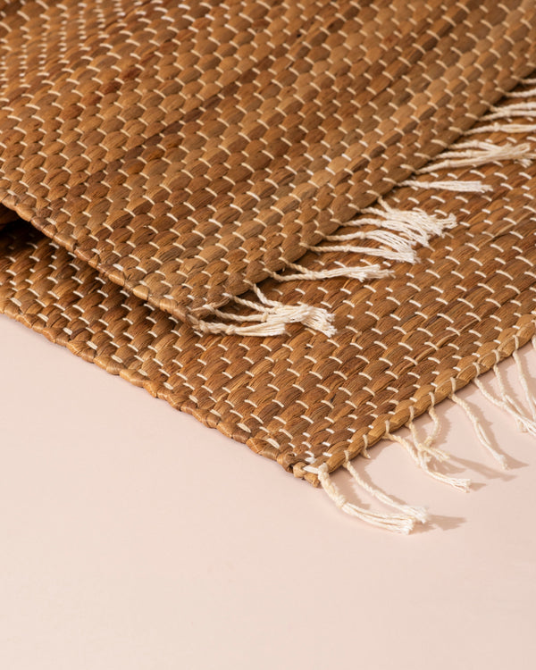 Tan woven water hyacinth table runner with textured interlaced pattern and white fringe edges, 122cm
