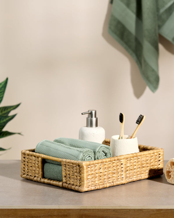 Water Hyacinth Tray with rolled green towels, soap dispenser, bamboo toothbrushes